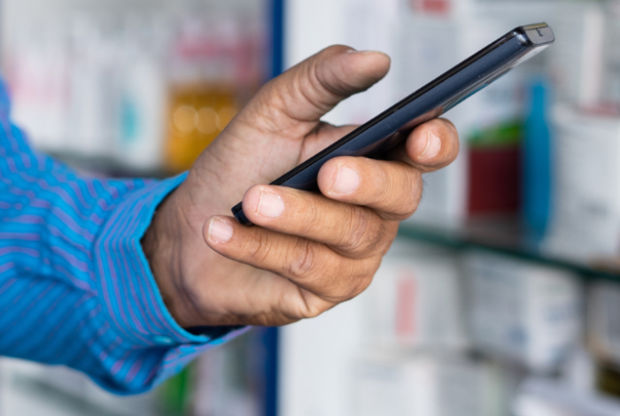 Man holding a phone in a pharmacy